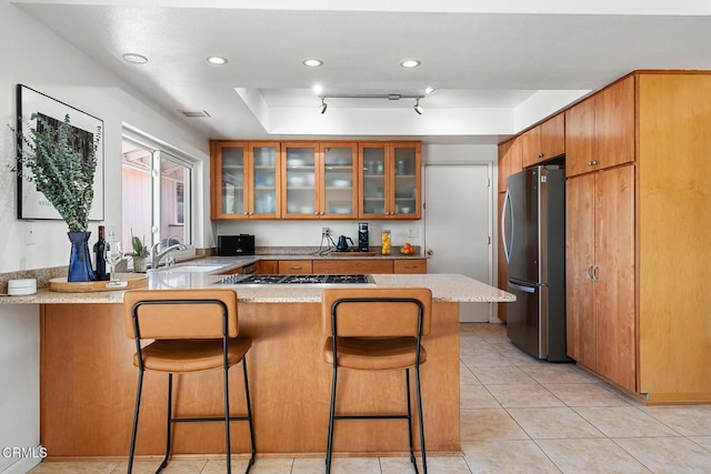 kitchen with a breakfast bar area, kitchen peninsula, stainless steel appliances, and a raised ceiling