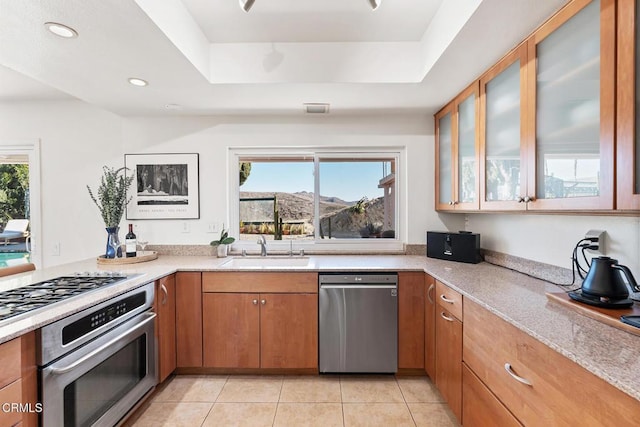 kitchen with light tile patterned floors, sink, a tray ceiling, and stainless steel appliances