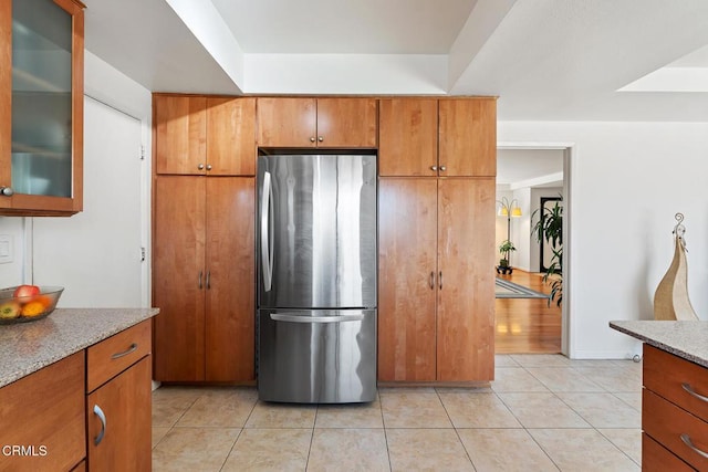 kitchen with light stone countertops, stainless steel refrigerator, and light tile patterned flooring