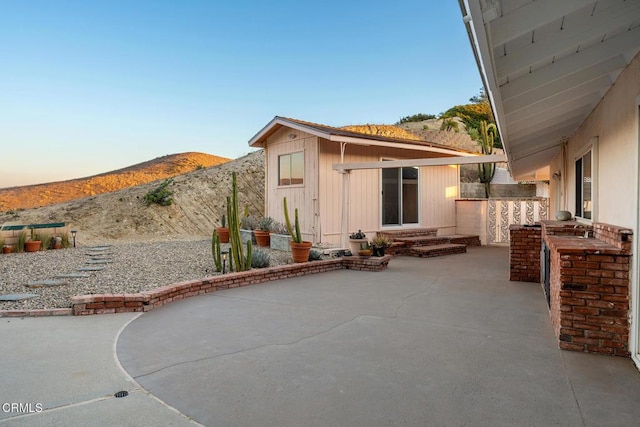 back house at dusk with a mountain view, an outdoor bar, and a patio