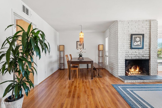 dining room featuring a brick fireplace and hardwood / wood-style flooring