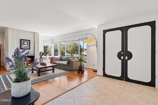 tiled living room featuring a brick fireplace and french doors