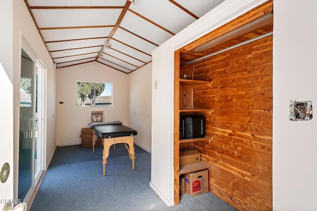 interior space featuring carpet, vaulted ceiling, and wooden walls