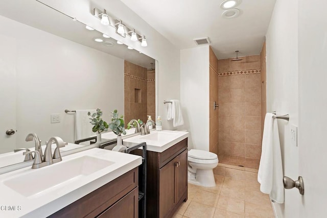 bathroom with tile patterned floors, vanity, a tile shower, and toilet