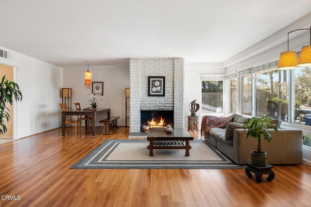 living room with a brick fireplace and hardwood / wood-style floors