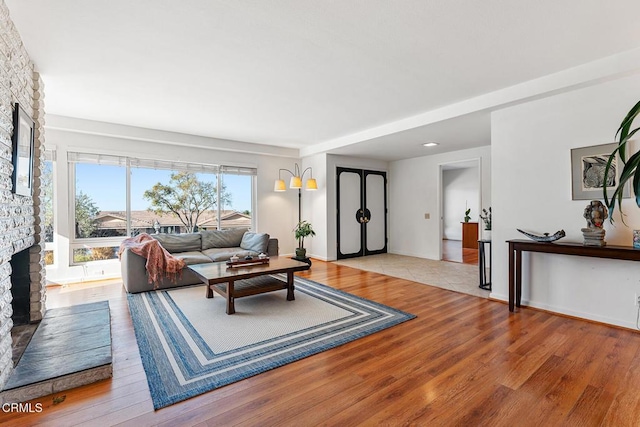 living room featuring light wood-type flooring and a brick fireplace