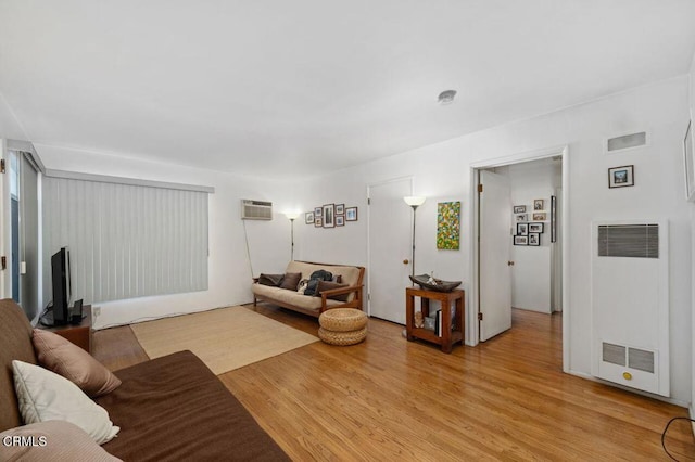 living room with light hardwood / wood-style flooring and a wall unit AC