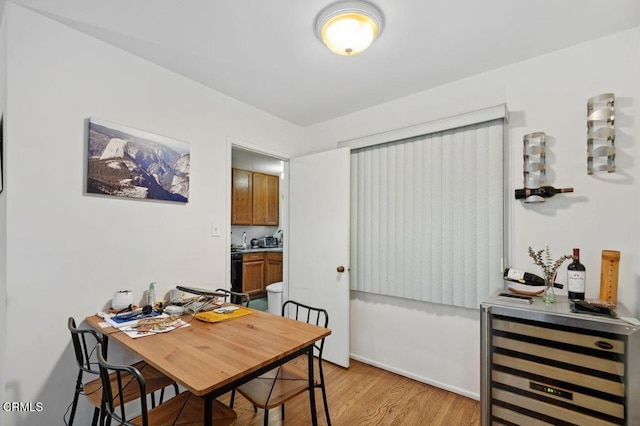 dining space featuring beverage cooler and light hardwood / wood-style flooring