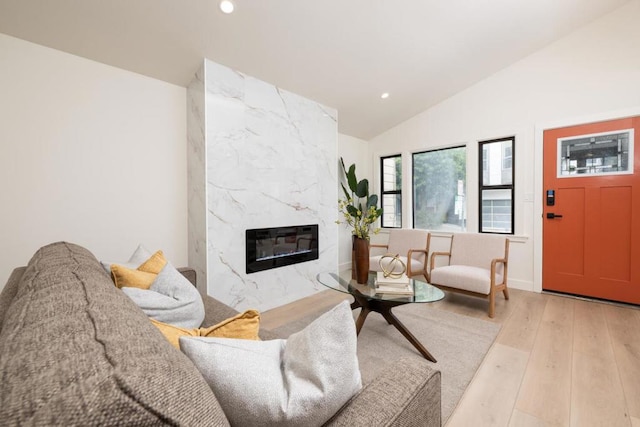 living room with heating unit, a high end fireplace, wood-type flooring, and vaulted ceiling