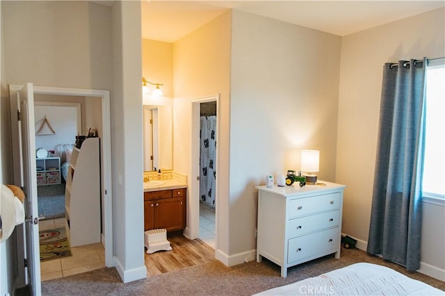 bedroom with sink, light colored carpet, and ensuite bathroom