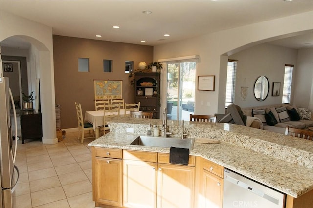 kitchen featuring sink, light tile patterned floors, dishwashing machine, and light stone counters