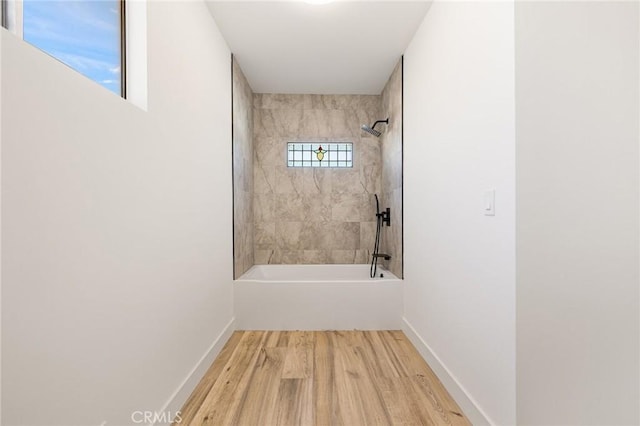 bathroom featuring wood-type flooring and tiled shower / bath combo