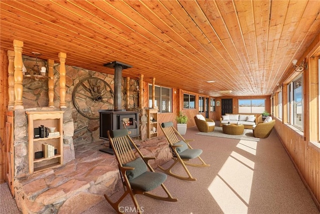 sunroom with a wood stove and wooden ceiling