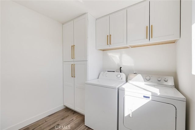 laundry room with cabinets, separate washer and dryer, and light hardwood / wood-style flooring