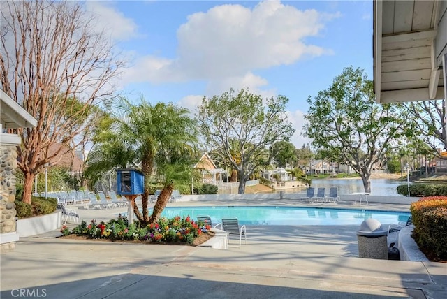 view of pool with a water view and a patio