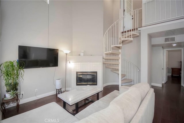 living room featuring dark hardwood / wood-style flooring, a tile fireplace, and a high ceiling