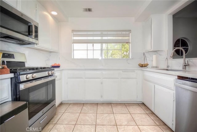 kitchen featuring light tile patterned floors, sink, white cabinets, and stainless steel appliances