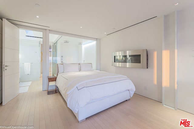 bedroom featuring floor to ceiling windows and light hardwood / wood-style floors