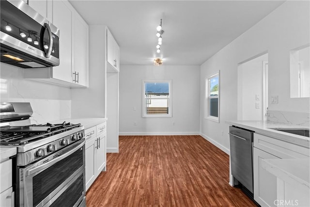 kitchen with stainless steel appliances, dark hardwood / wood-style floors, light stone countertops, and white cabinets