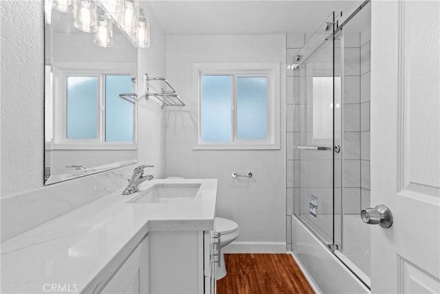 full bathroom with vanity, hardwood / wood-style flooring, combined bath / shower with glass door, and toilet