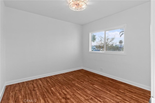 spare room featuring wood-type flooring and a chandelier