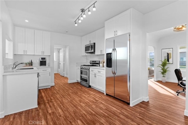 kitchen featuring sink, appliances with stainless steel finishes, track lighting, white cabinets, and light wood-type flooring