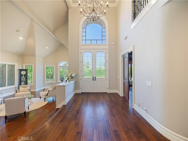 entrance foyer featuring crown molding, french doors, dark wood-type flooring, a towering ceiling, and a notable chandelier