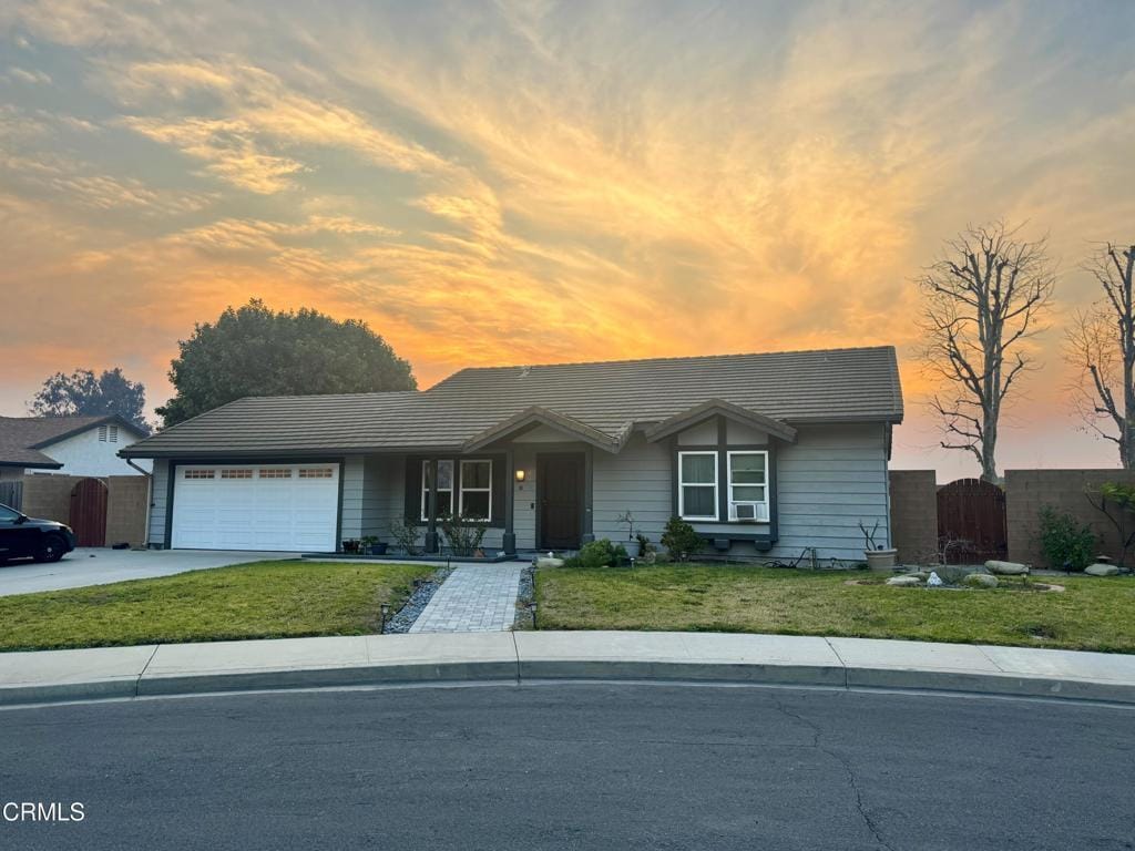 ranch-style house with a garage and a lawn