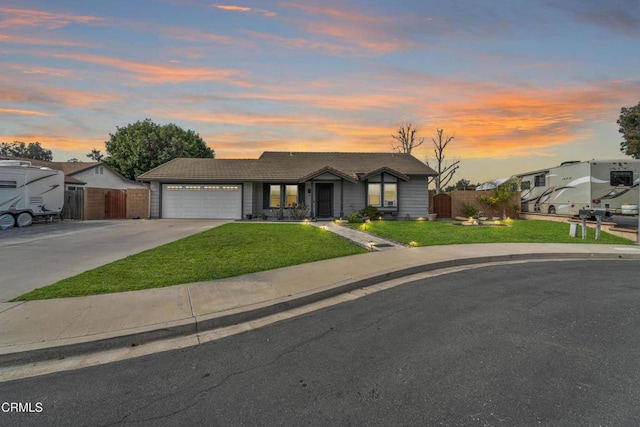 view of front of home with a tile roof, concrete driveway, an attached garage, fence, and a front lawn