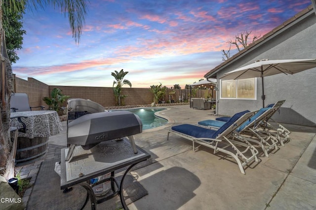patio terrace at dusk featuring a fenced backyard and a fenced in pool