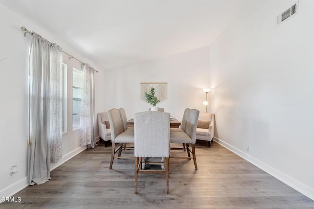 dining area with baseboards, visible vents, and wood finished floors