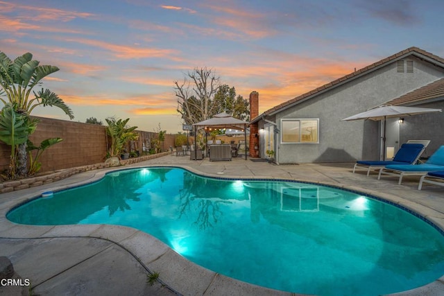 pool at dusk featuring central AC unit, a patio area, a gazebo, a fenced in pool, and a fenced backyard