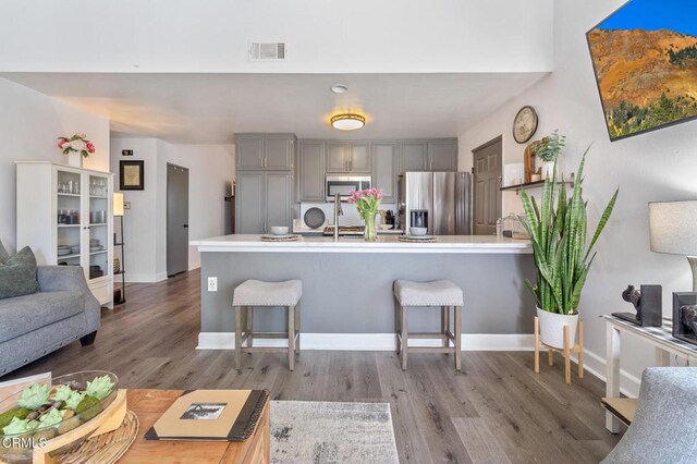 living room featuring visible vents, baseboards, and wood finished floors