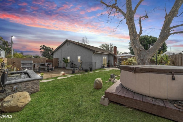 yard at dusk with a hot tub, a gazebo, and fence