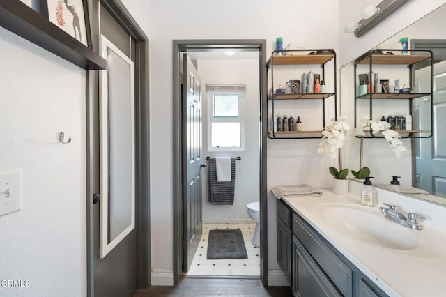 bathroom featuring vanity, baseboards, wood finished floors, and toilet