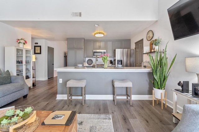 living area with baseboards, visible vents, and wood finished floors