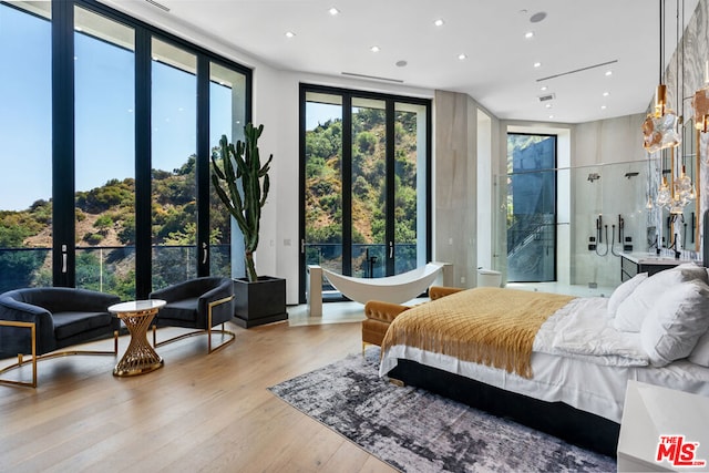 bedroom featuring french doors, a wall of windows, and light hardwood / wood-style flooring