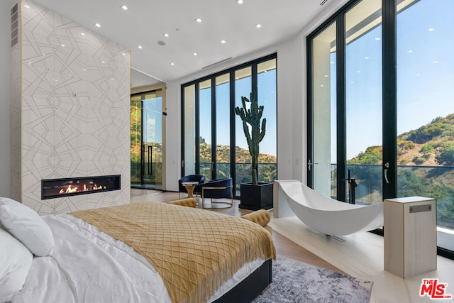 bedroom featuring a tile fireplace and floor to ceiling windows