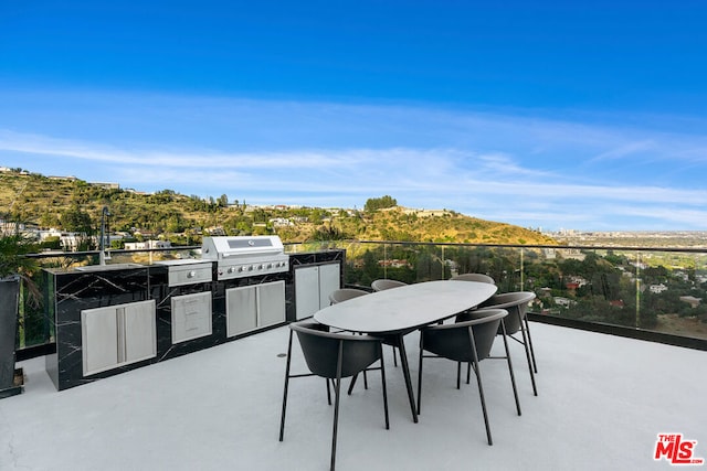 view of patio / terrace featuring a grill, an outdoor kitchen, and a mountain view