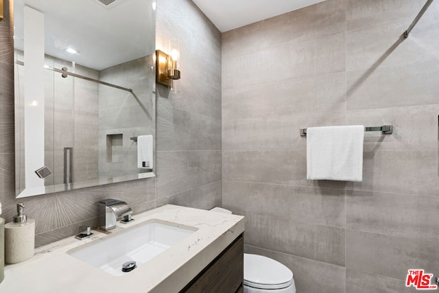 bathroom featuring an enclosed shower, vanity, decorative backsplash, tile walls, and toilet