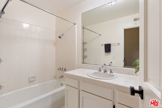 bathroom with tiled shower / bath combo and vanity