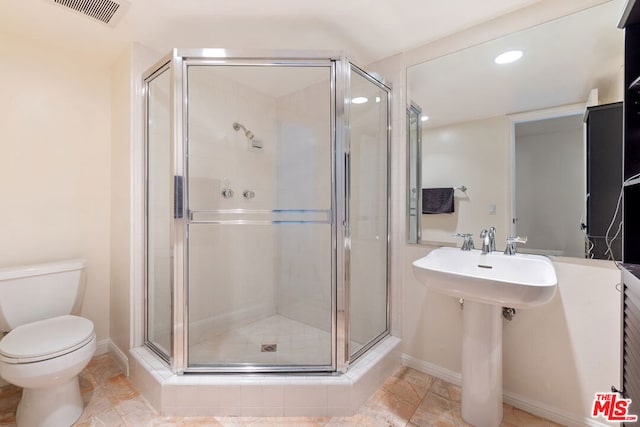 bathroom with a shower with shower door, sink, and toilet