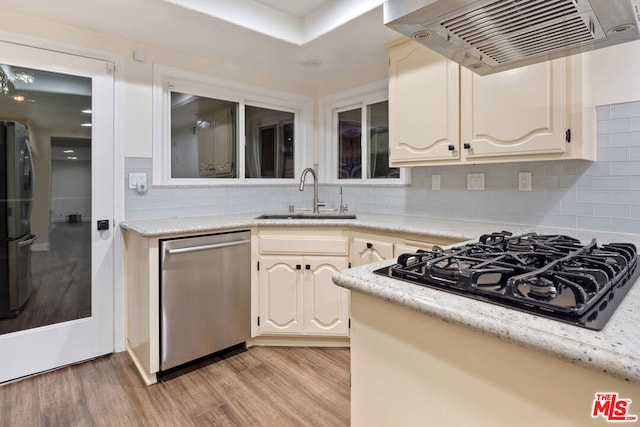 kitchen with light hardwood / wood-style floors, sink, wall chimney range hood, and appliances with stainless steel finishes