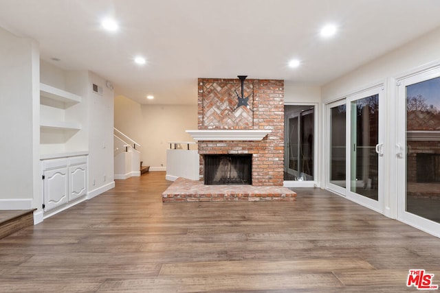 unfurnished living room featuring built in shelves, hardwood / wood-style floors, and a fireplace