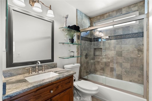 full bathroom featuring toilet, bath / shower combo with glass door, and vanity