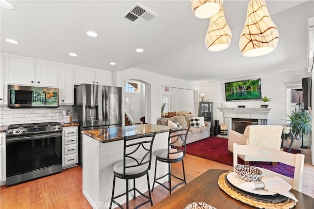 kitchen featuring a center island, a kitchen bar, light hardwood / wood-style flooring, appliances with stainless steel finishes, and white cabinets