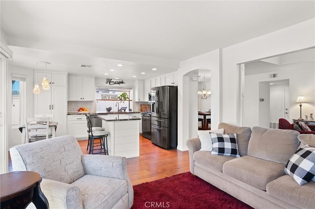 living room featuring an inviting chandelier, light hardwood / wood-style floors, and sink