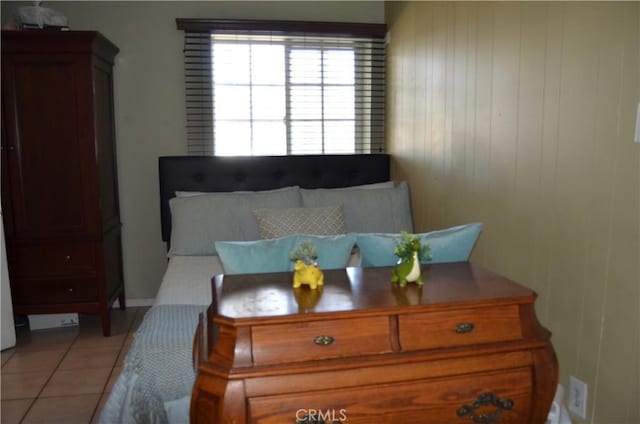 bedroom featuring light tile patterned flooring and wood walls