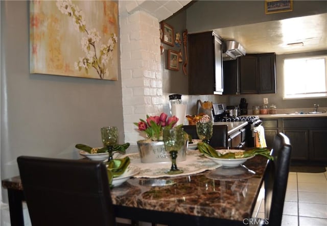 kitchen featuring stainless steel gas range, light tile patterned flooring, dark brown cabinets, and sink