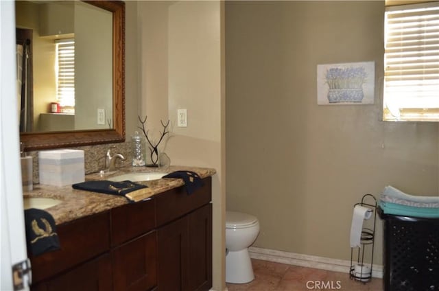 bathroom with a wealth of natural light, toilet, vanity, and tile patterned flooring